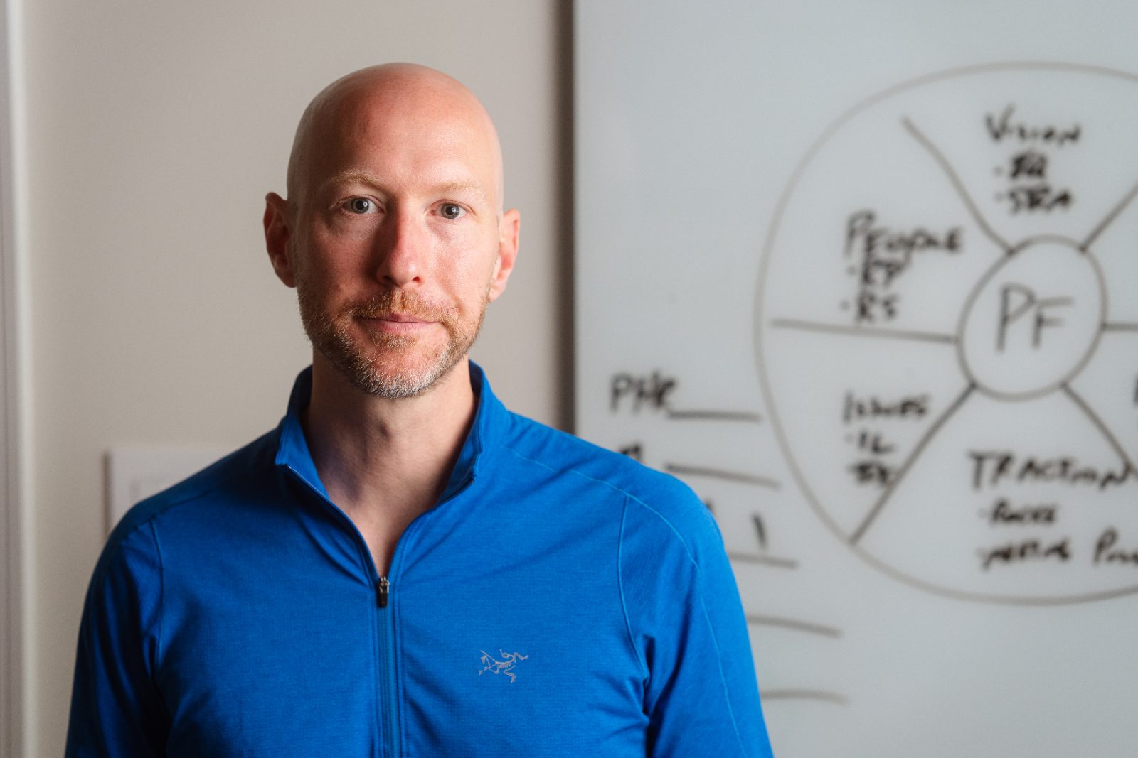 Portrait of Dennis O&rsquo;Donnell in a blue quarter-zip, an EOS whiteboard behind him